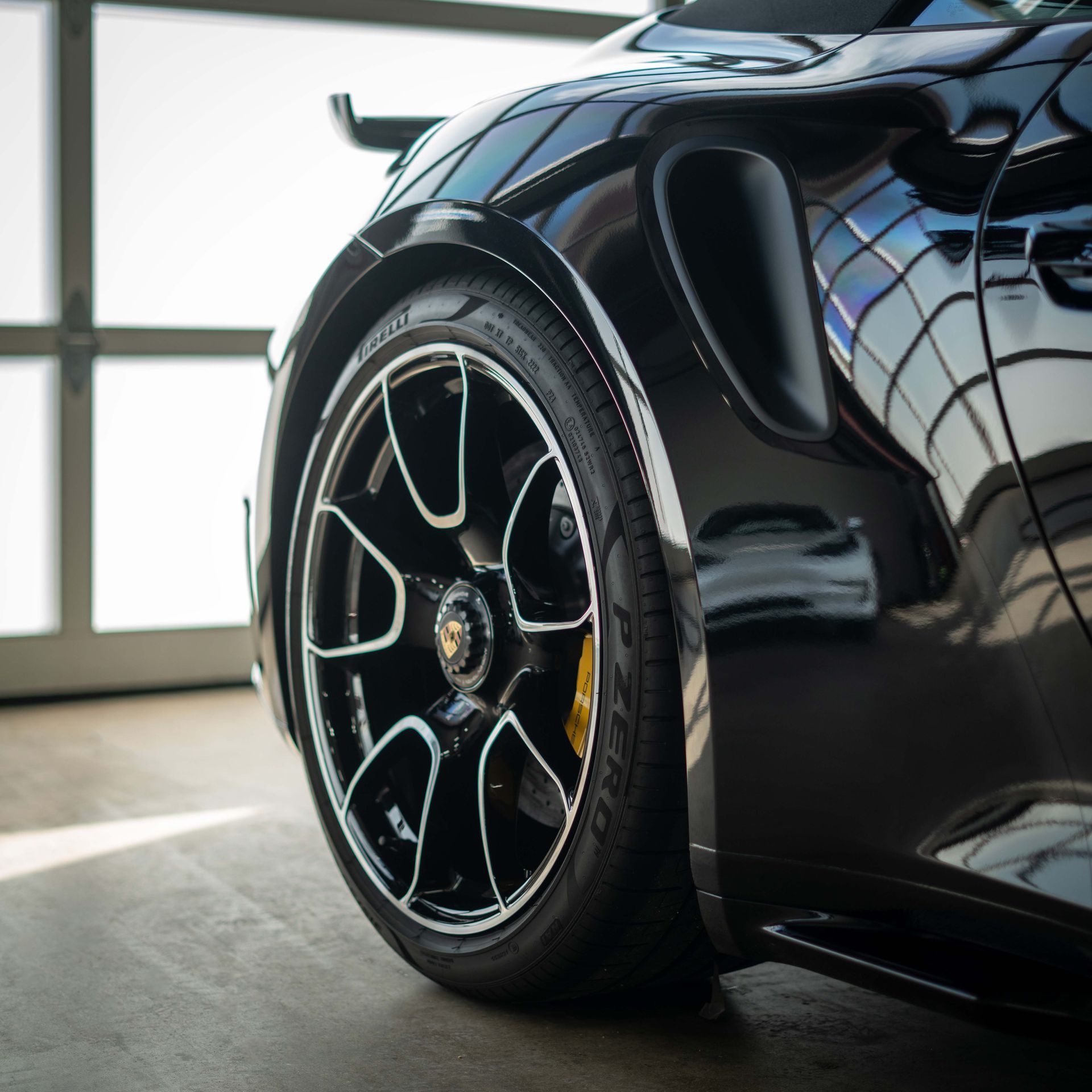 A black sports car is parked in a garage