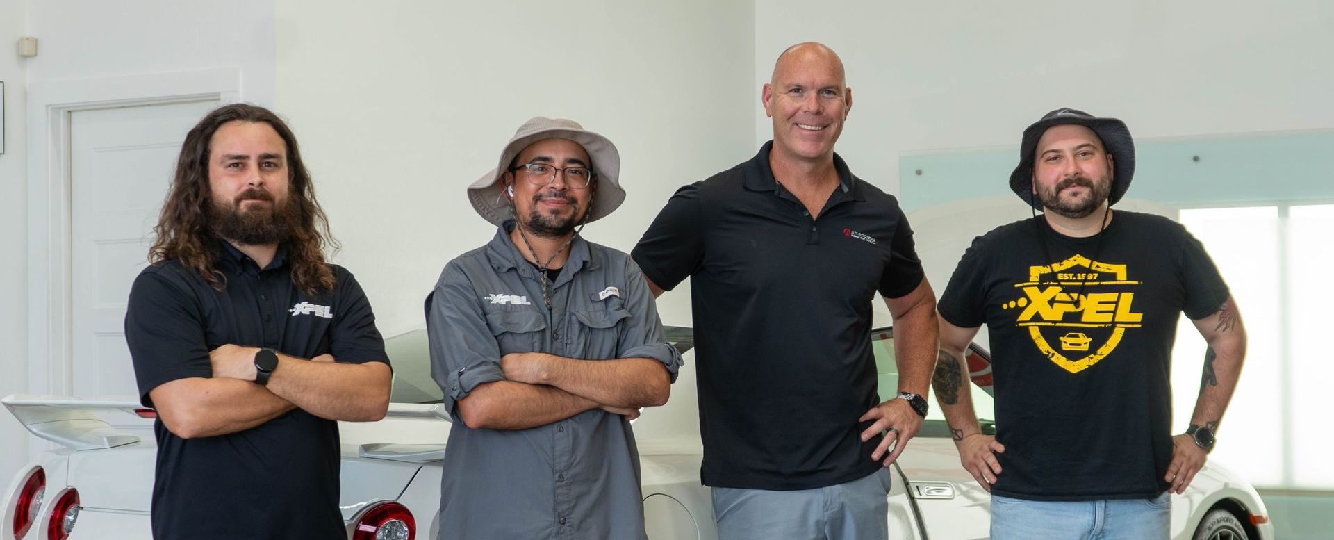 A group of men are standing next to each other in front of a car.