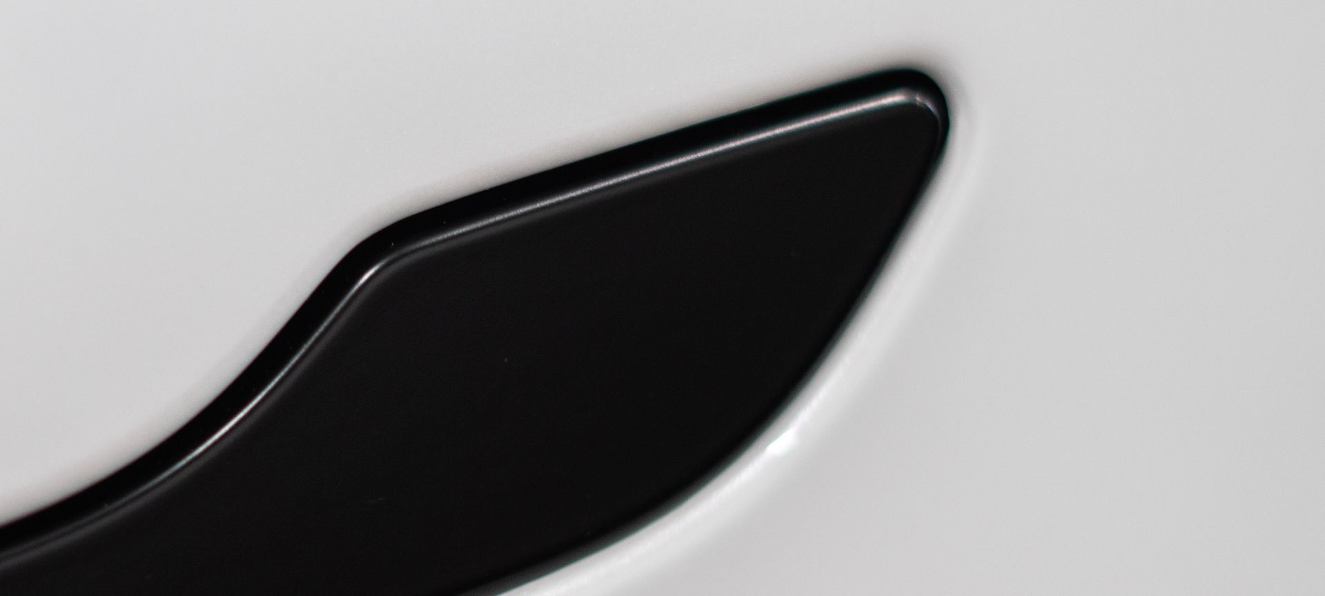 a close up of a black handle on a white surface .