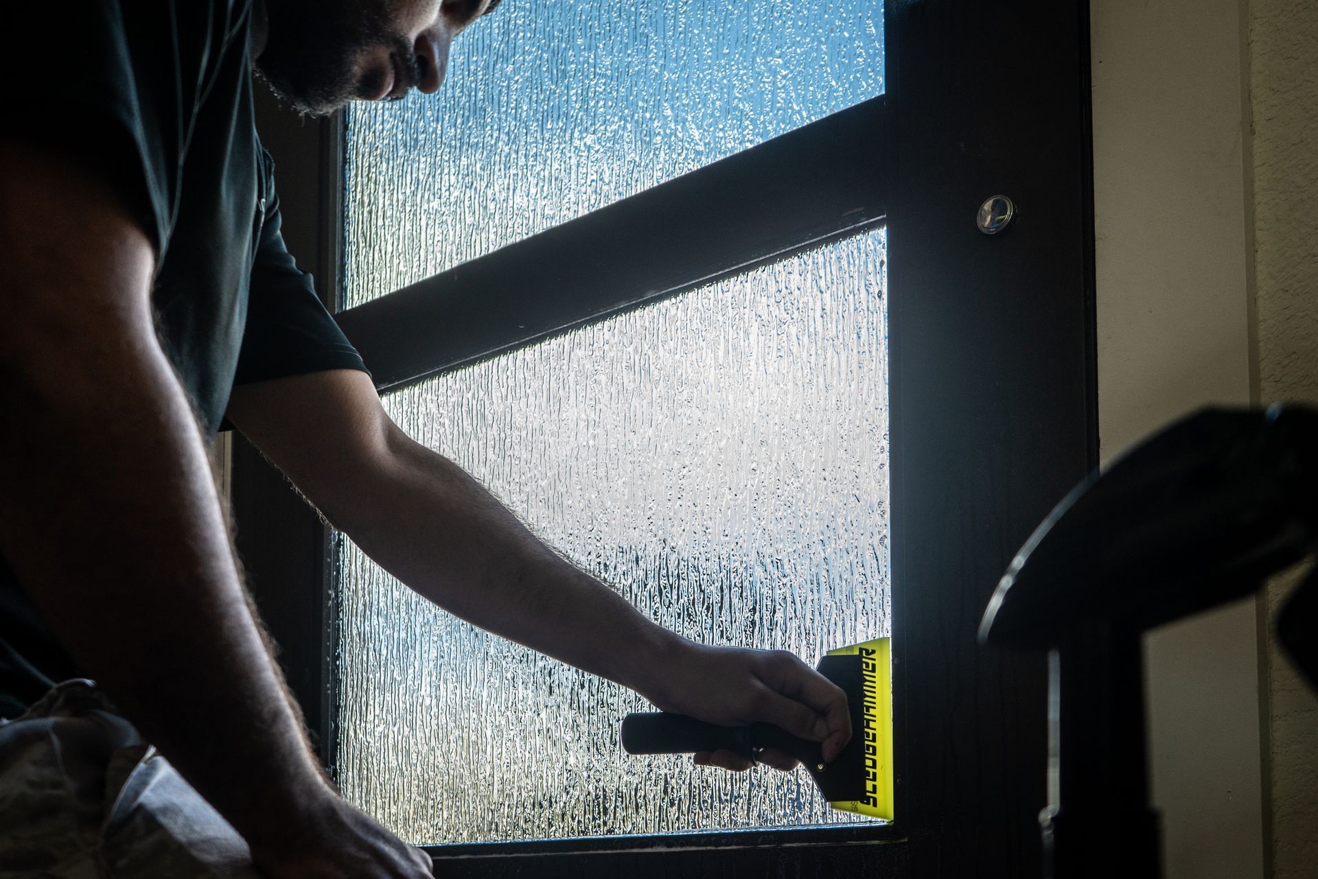 a man is cleaning a window with a squeegee .