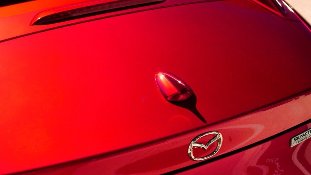 A close up of the rear end of a red mazda car.