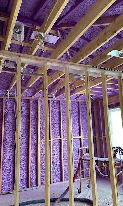 A house is being built with purple insulation on the walls and ceiling.