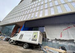 A white truck is parked in front of a large building under construction.