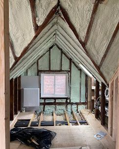 The attic is being insulated and has a window.