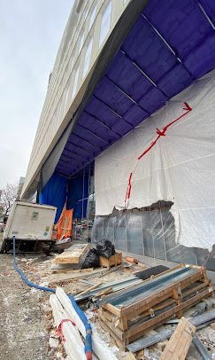 A building under construction with a purple tarp on the side of it.
