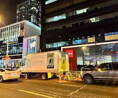 A truck is parked on the side of the road in front of a building at night.