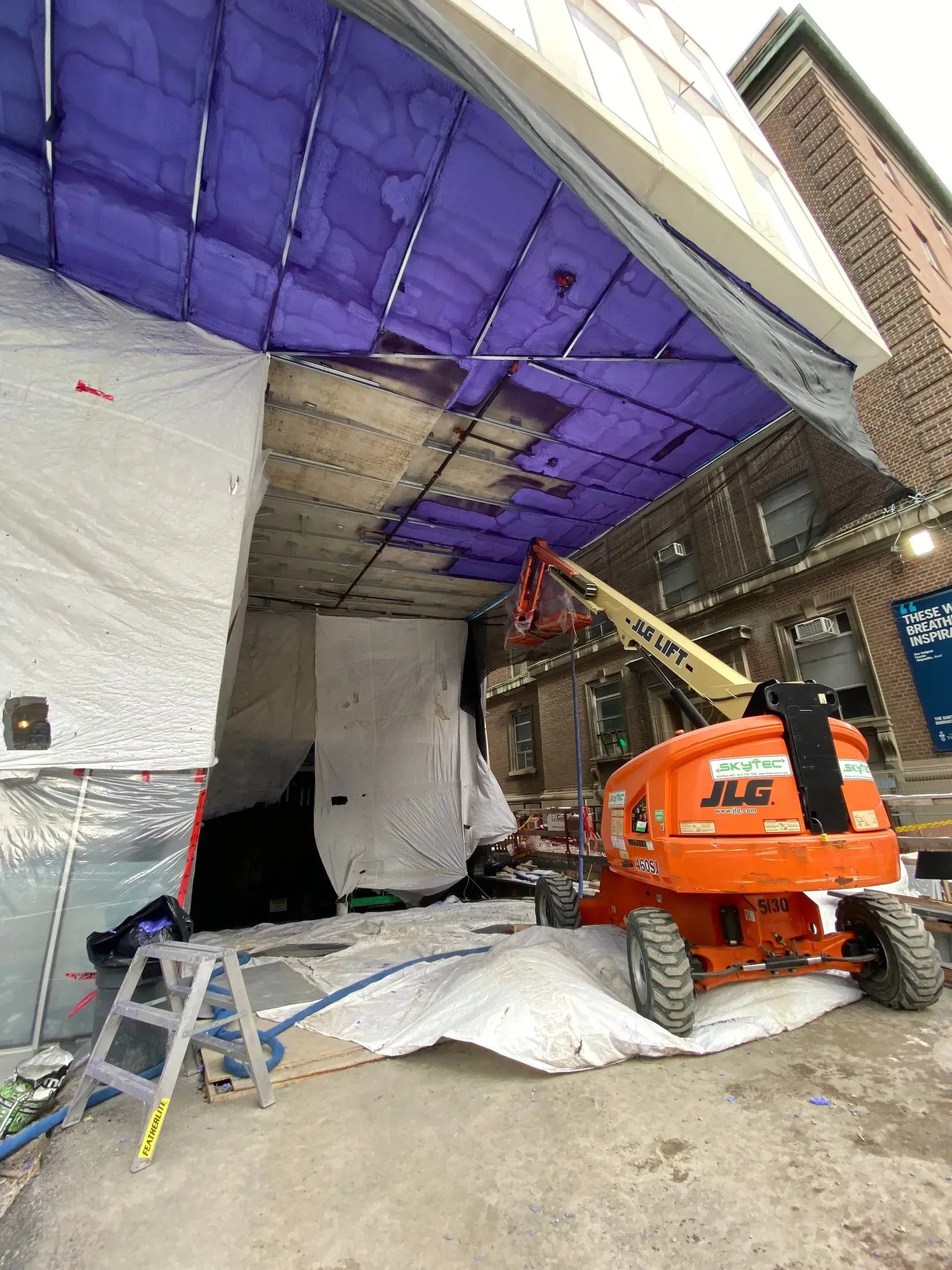 A purple tarp is covering the ceiling of a building.