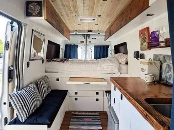 The inside of a van with a bed and a kitchen.