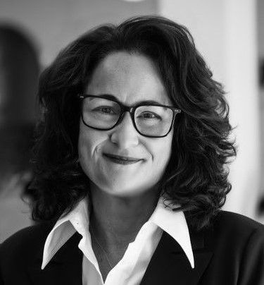 A black and white photo of a woman wearing glasses and a suit.