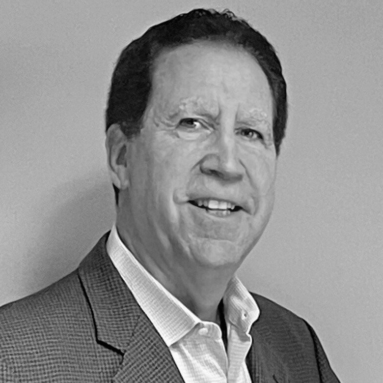 A man in a suit and white shirt is smiling in a black and white photo.