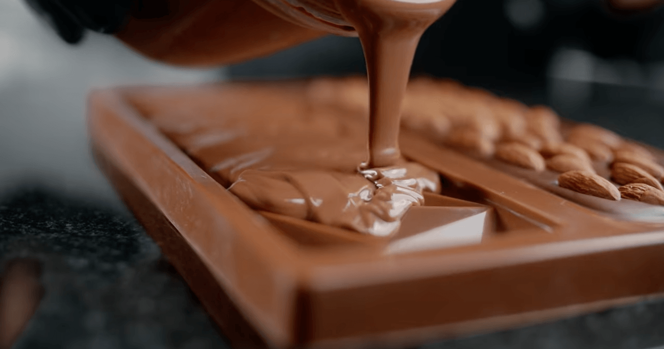 A person is pouring chocolate into a chocolate bar.