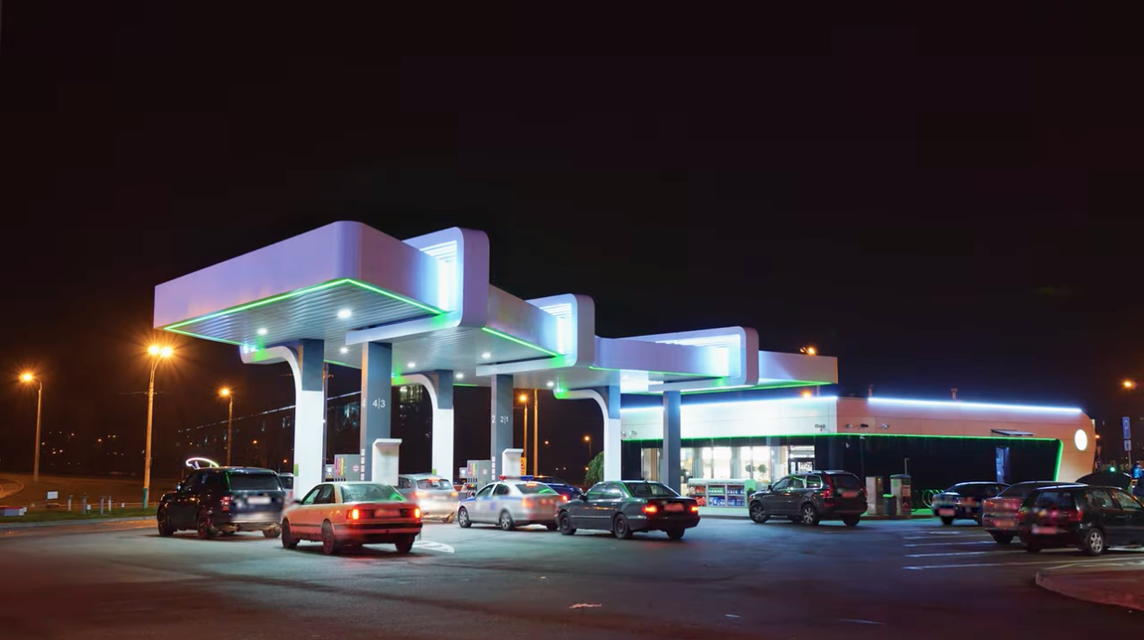A gas station at night with cars parked in front of it.