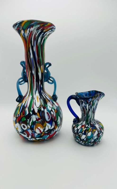 Due vasi di vetro colorati e screziati, uno alto con manici, l'altro piccolo con un manico.