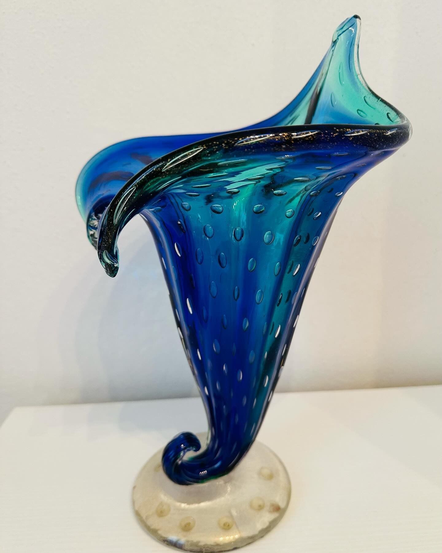 Vaso in vetro artistico blu e verde acqua con dettagli a bolle, su piedistallo bianco.