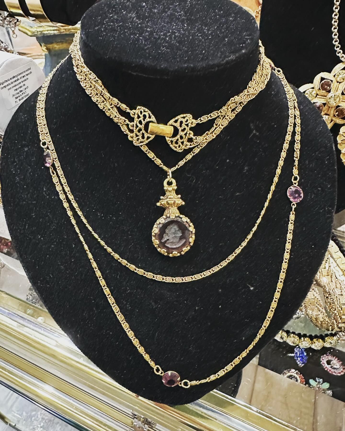 Collane d'oro su un busto portagioie nero. Include più strati e dettagli in ametista.