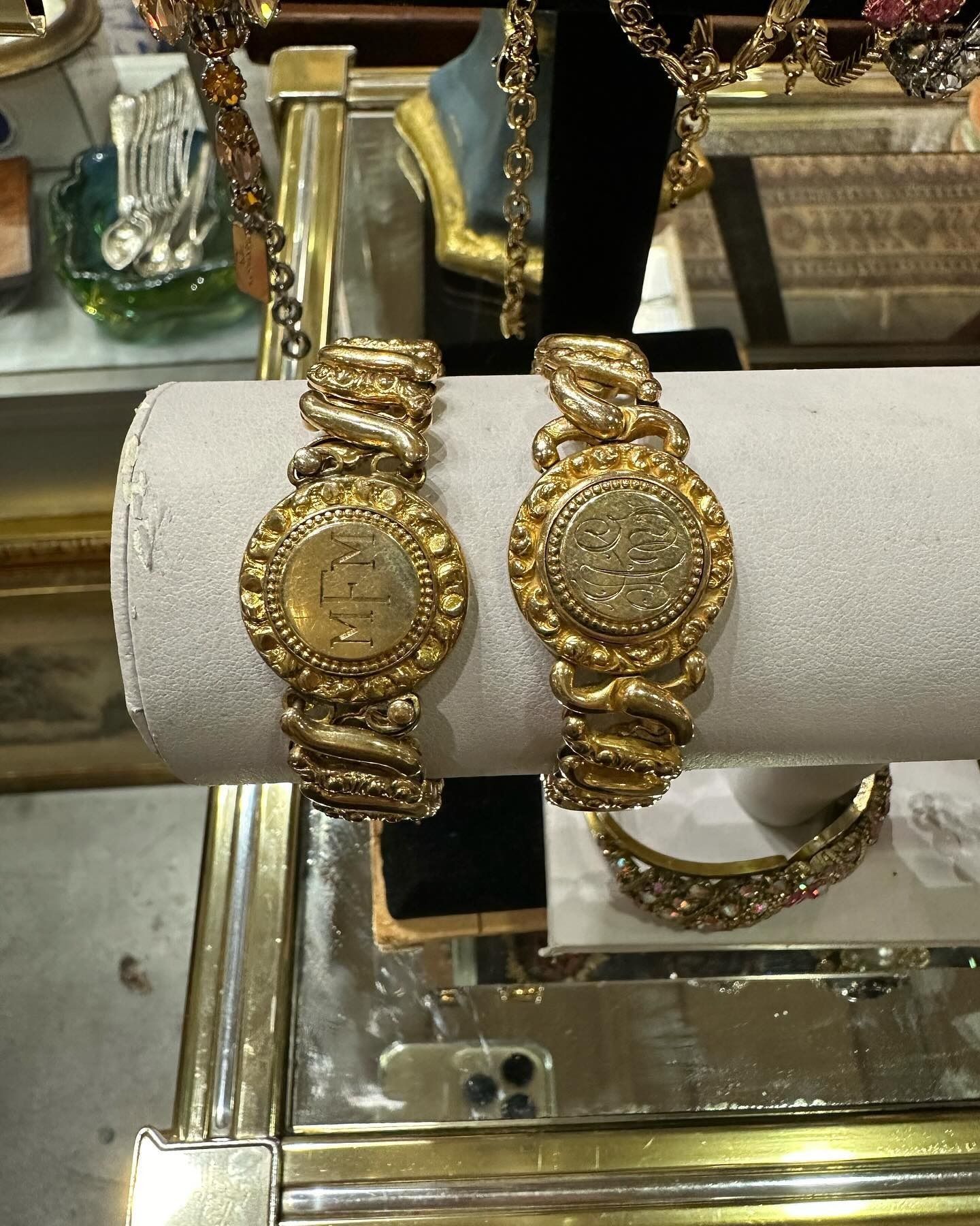 Due braccialetti d'oro con dettagli elaborati esposti su un espositore.