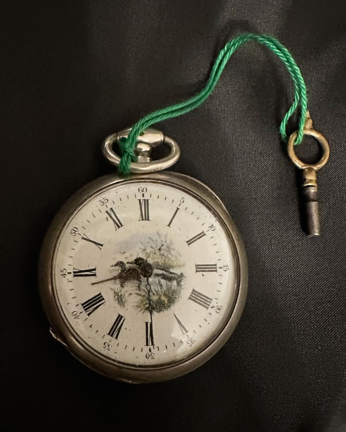 Orologio da tasca in argento con cordino verde e chiave; quadrante dipinto raffigurante un uccello.
