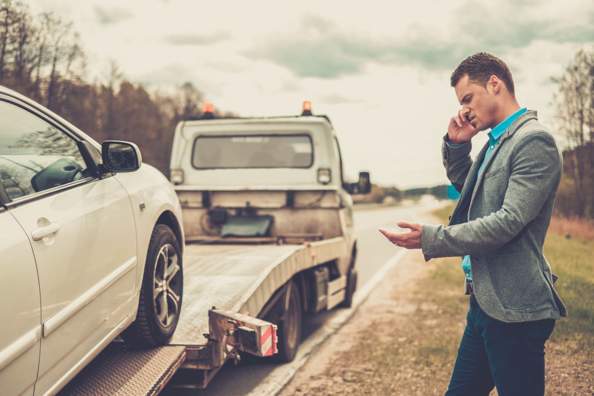 man calling while tow truck picking