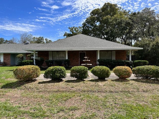 A picture of a house with bushes lined up in front of it in Mandeville, LA.
