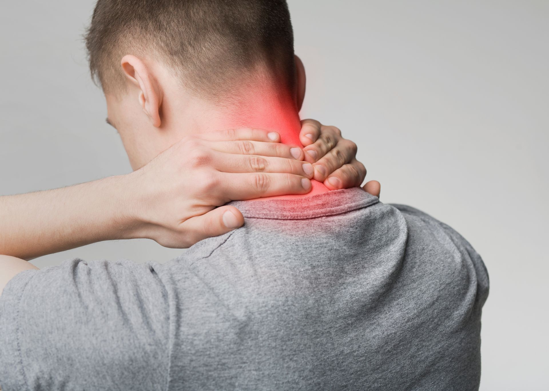 Person holding the back of their neck, with a red highlight indicating pain or strain