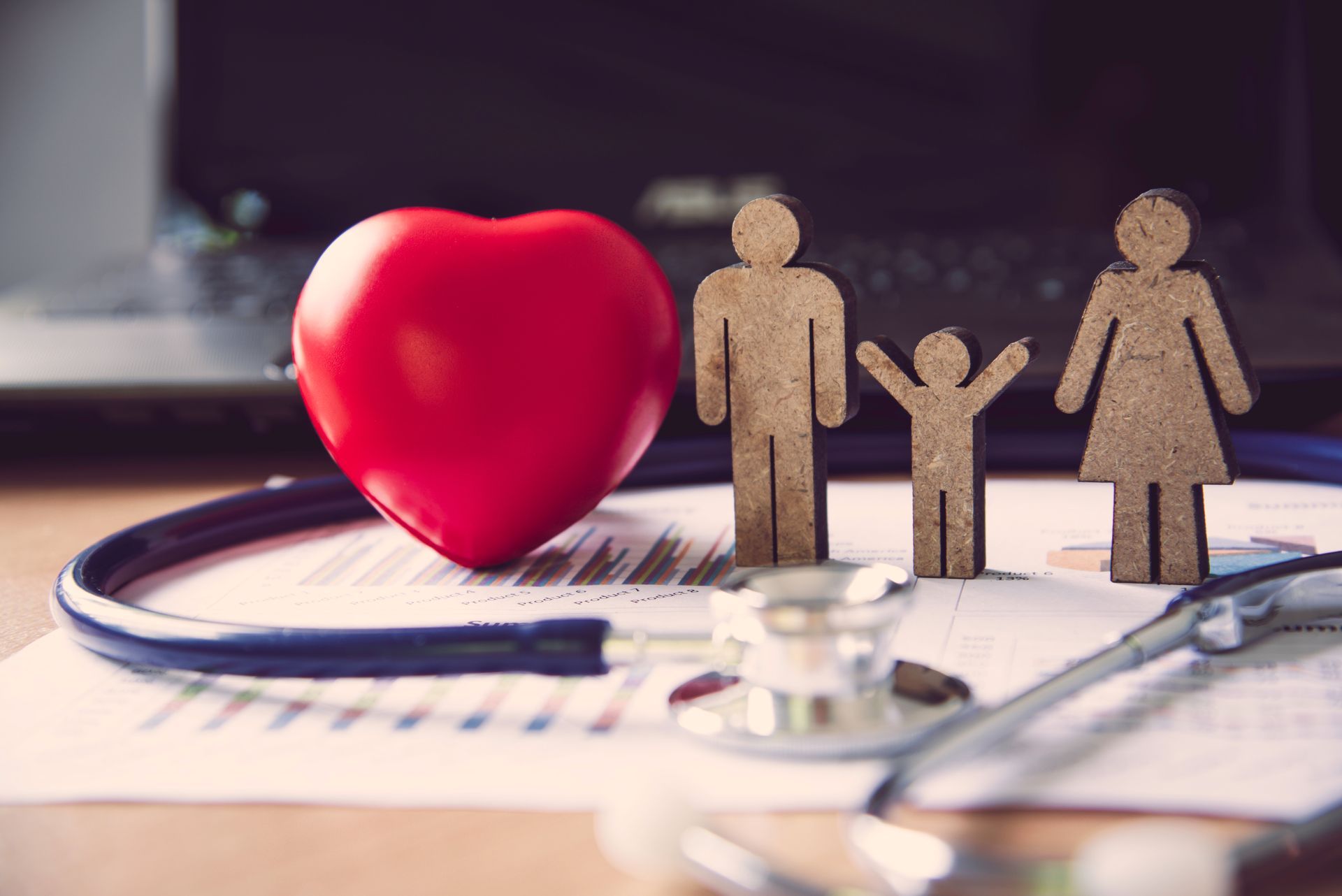 Red heart beside paper family figures and a stethoscope on a medical form