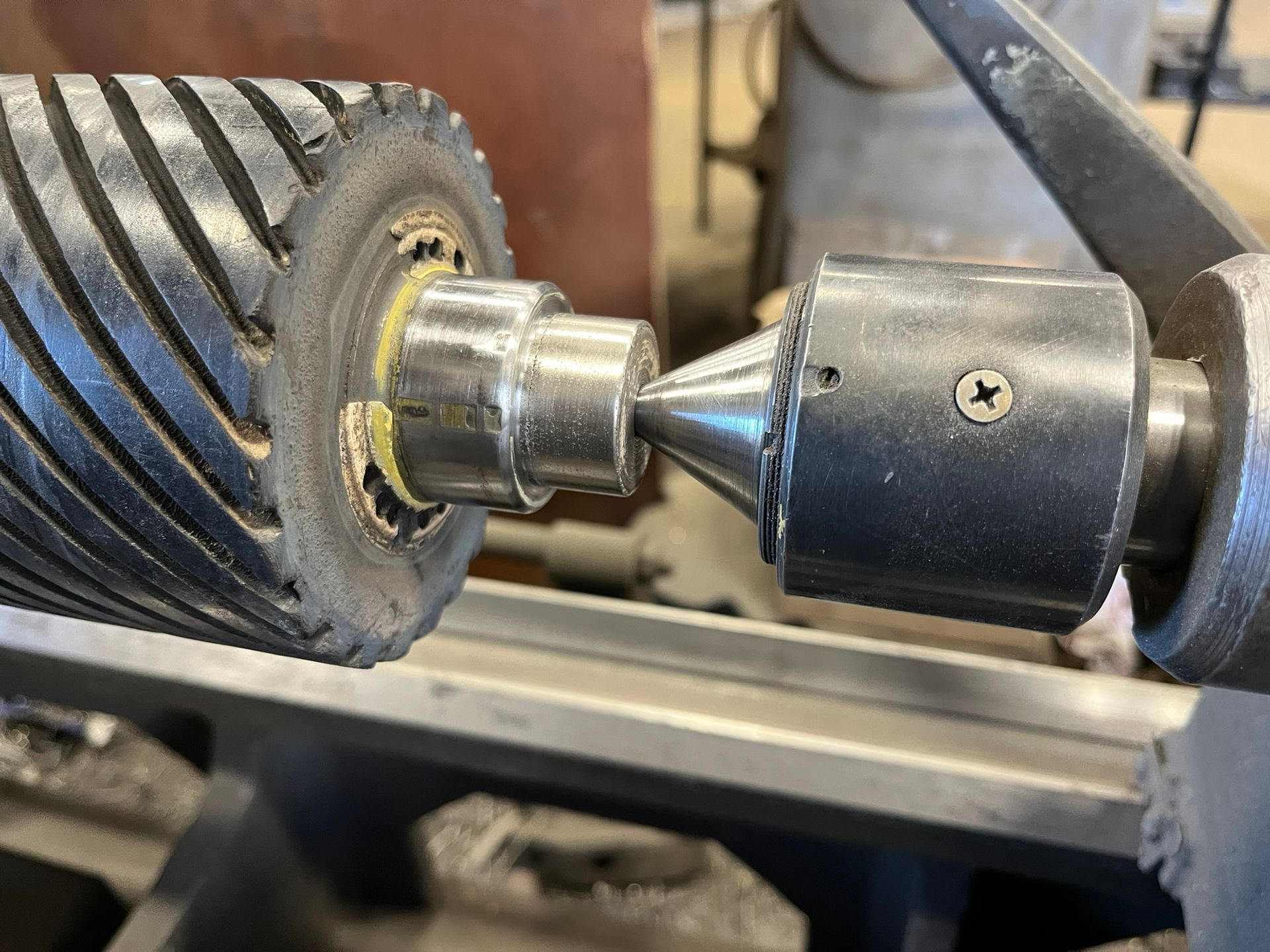 Close-up of a metal drill chuck gripping a shiny cylindrical shaft on a machine
