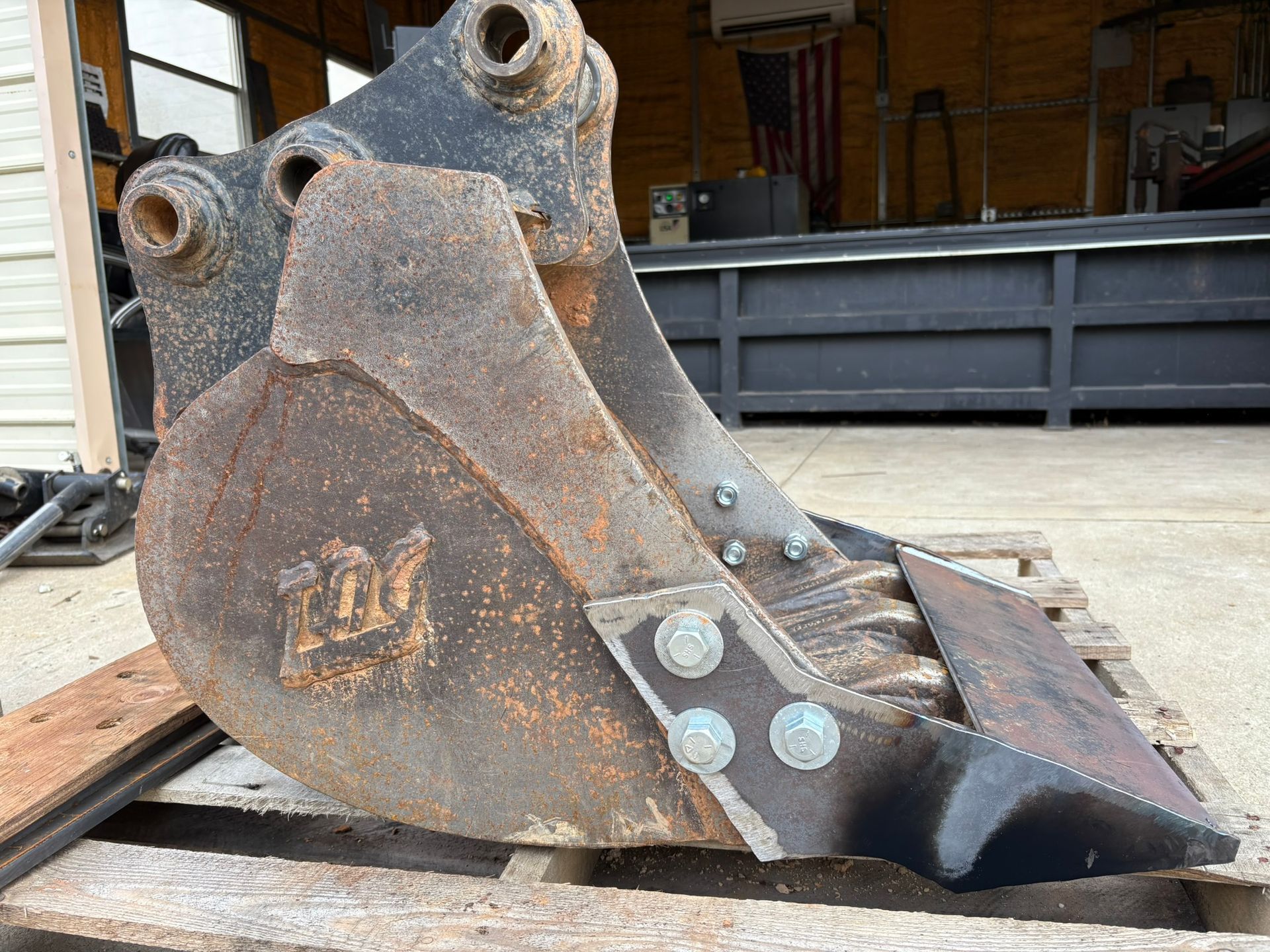 Rusty excavator bucket on wooden pallets in a garage or workshop setting