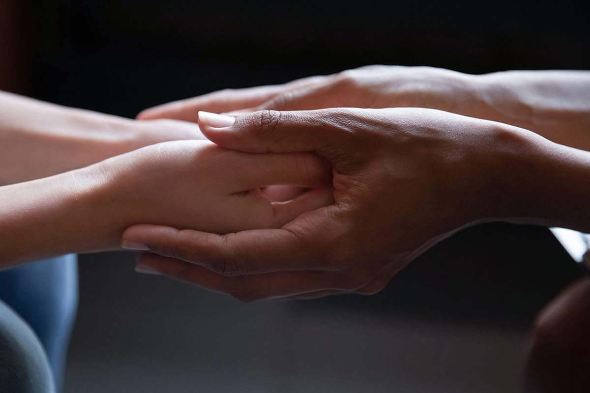 Hands of different skin tones clasped together, providing comfort and support.