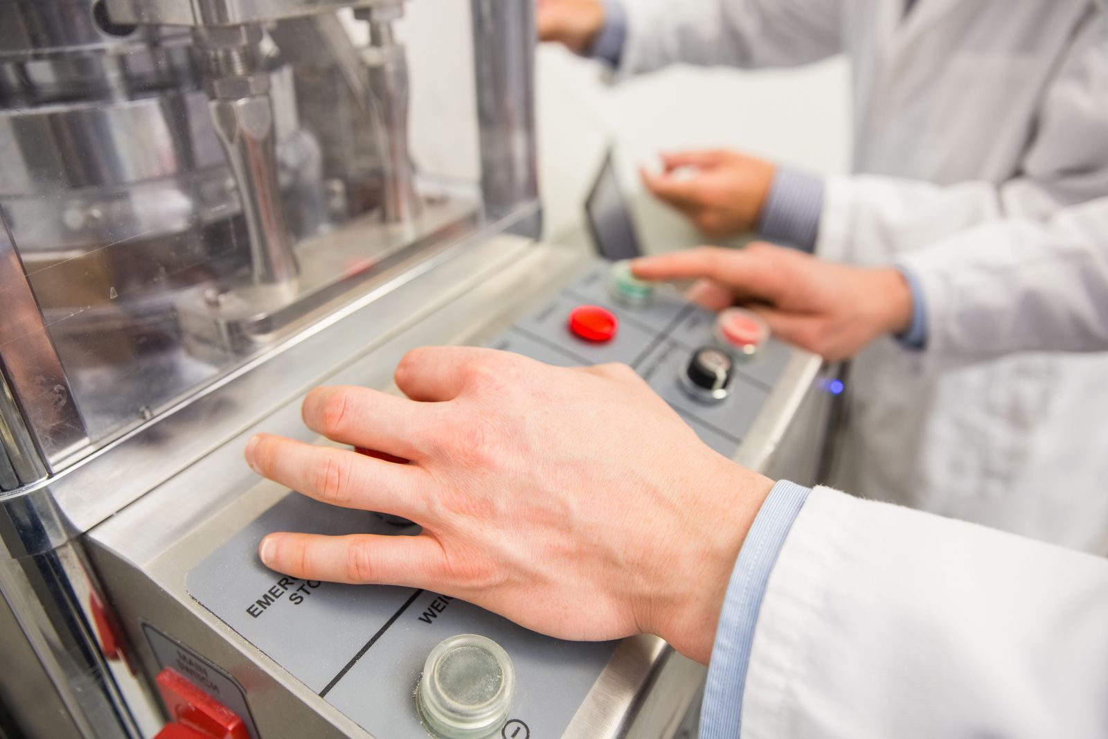 A person is pressing a button on a machine in a lab.