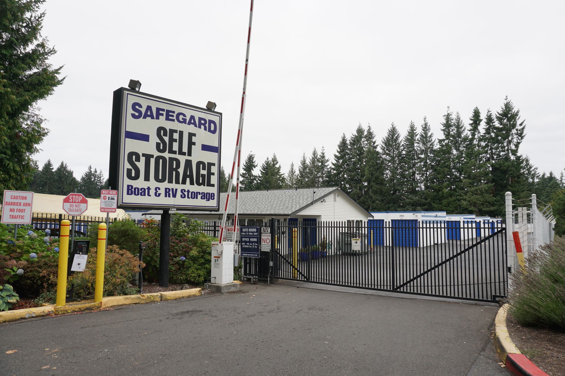 Entrance to Safeguard Self Storage facility with a sign, gate, and small building.