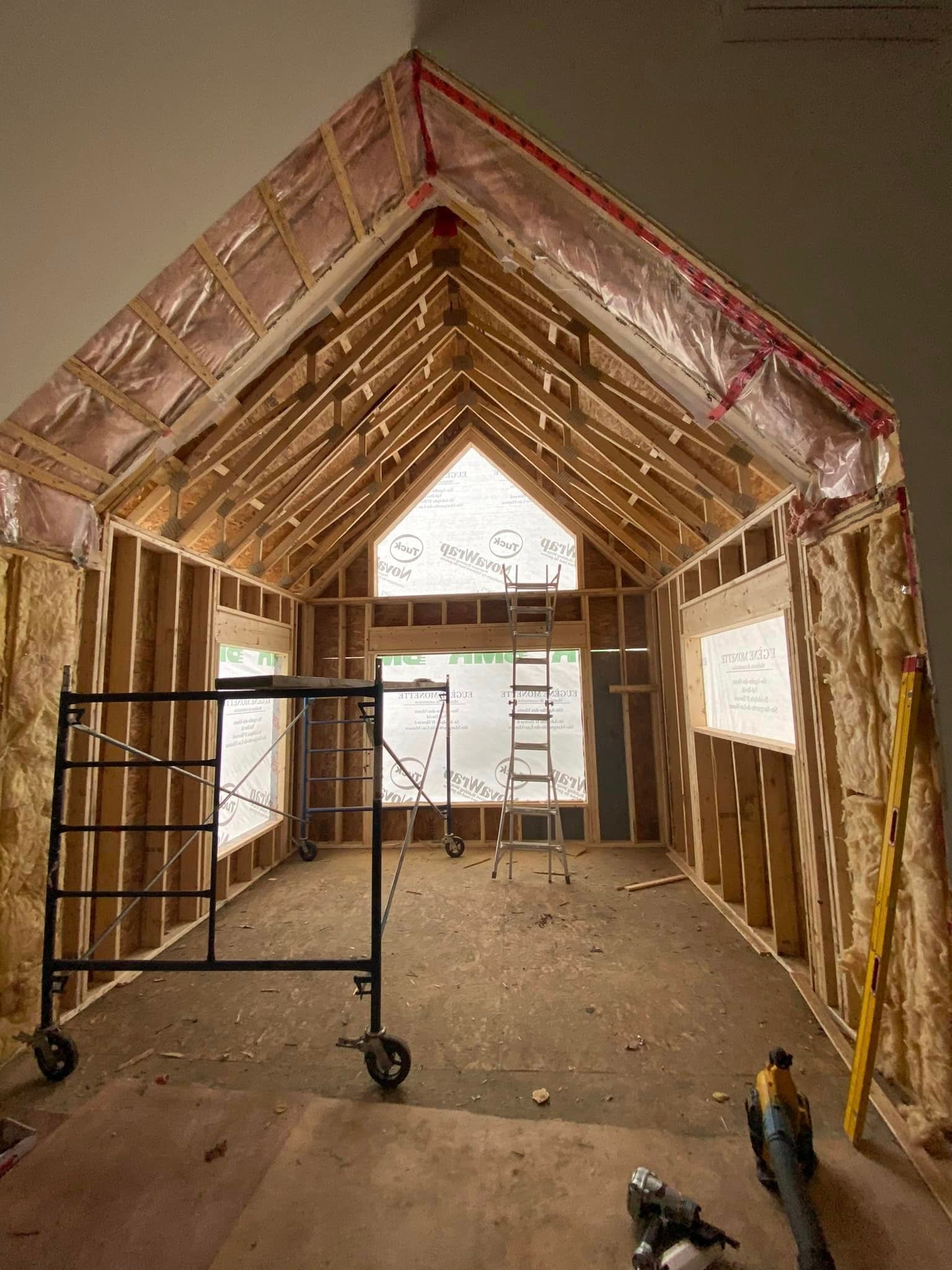 Une pièce en construction avec un échafaudage et des outils au sol.