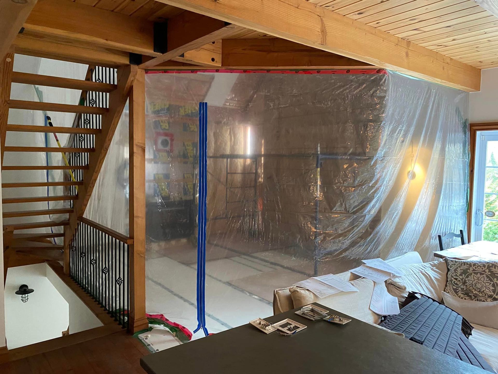 Un salon avec un escalier et un revêtement plastique au sol.