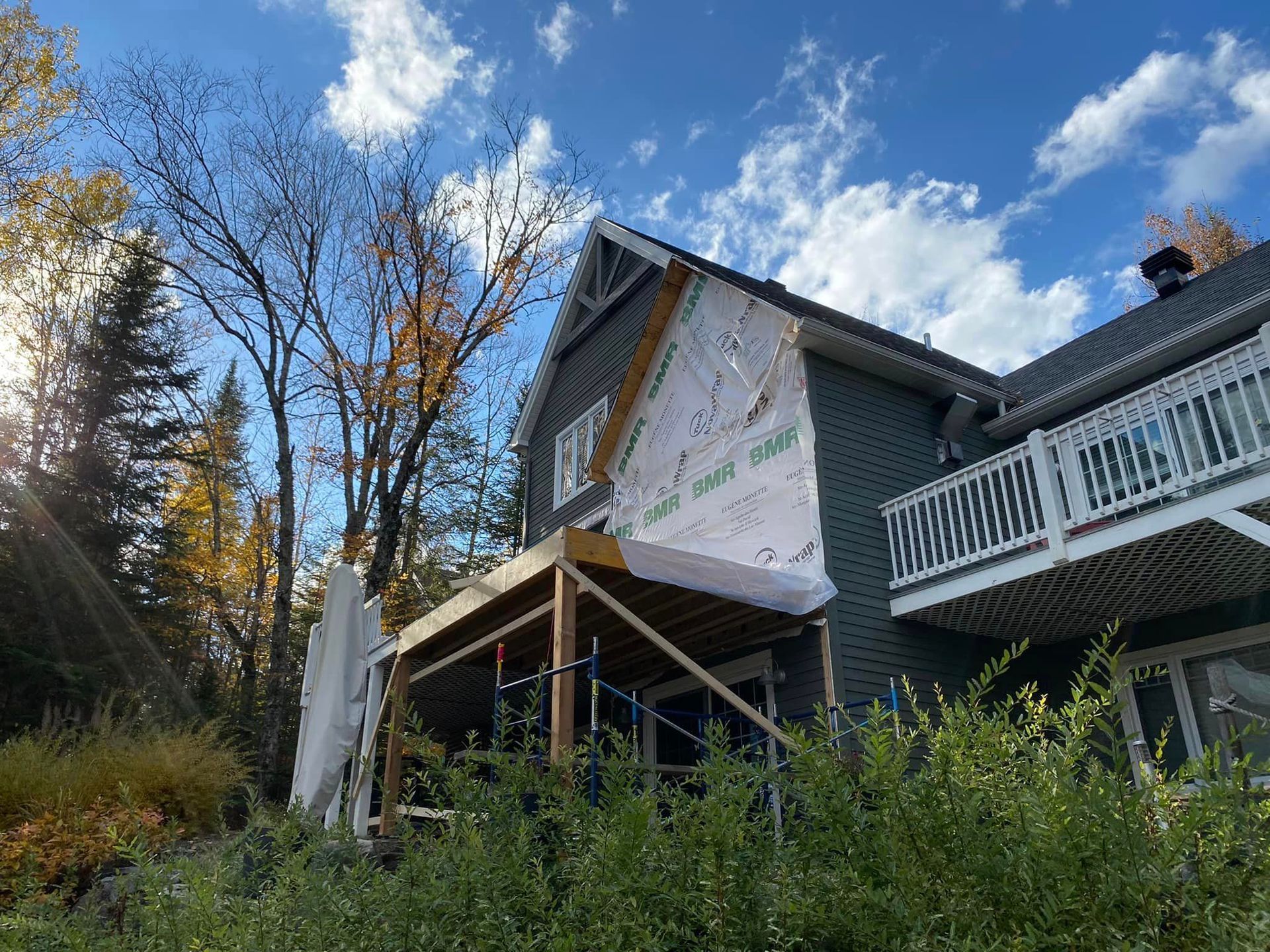 Une maison est en cours de rénovation avec un porche et un balcon.