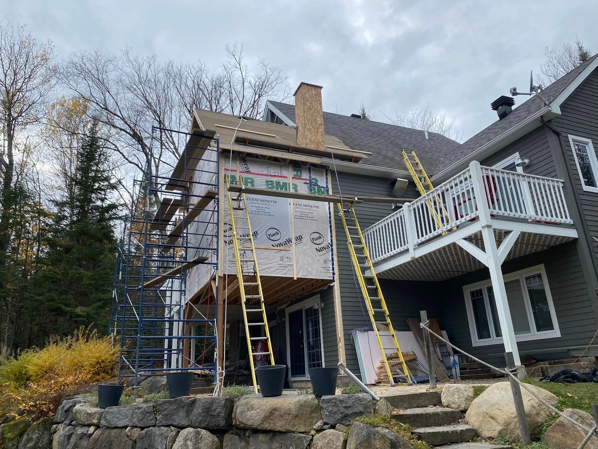 Une maison est en cours de rénovation avec une terrasse et des échafaudages.