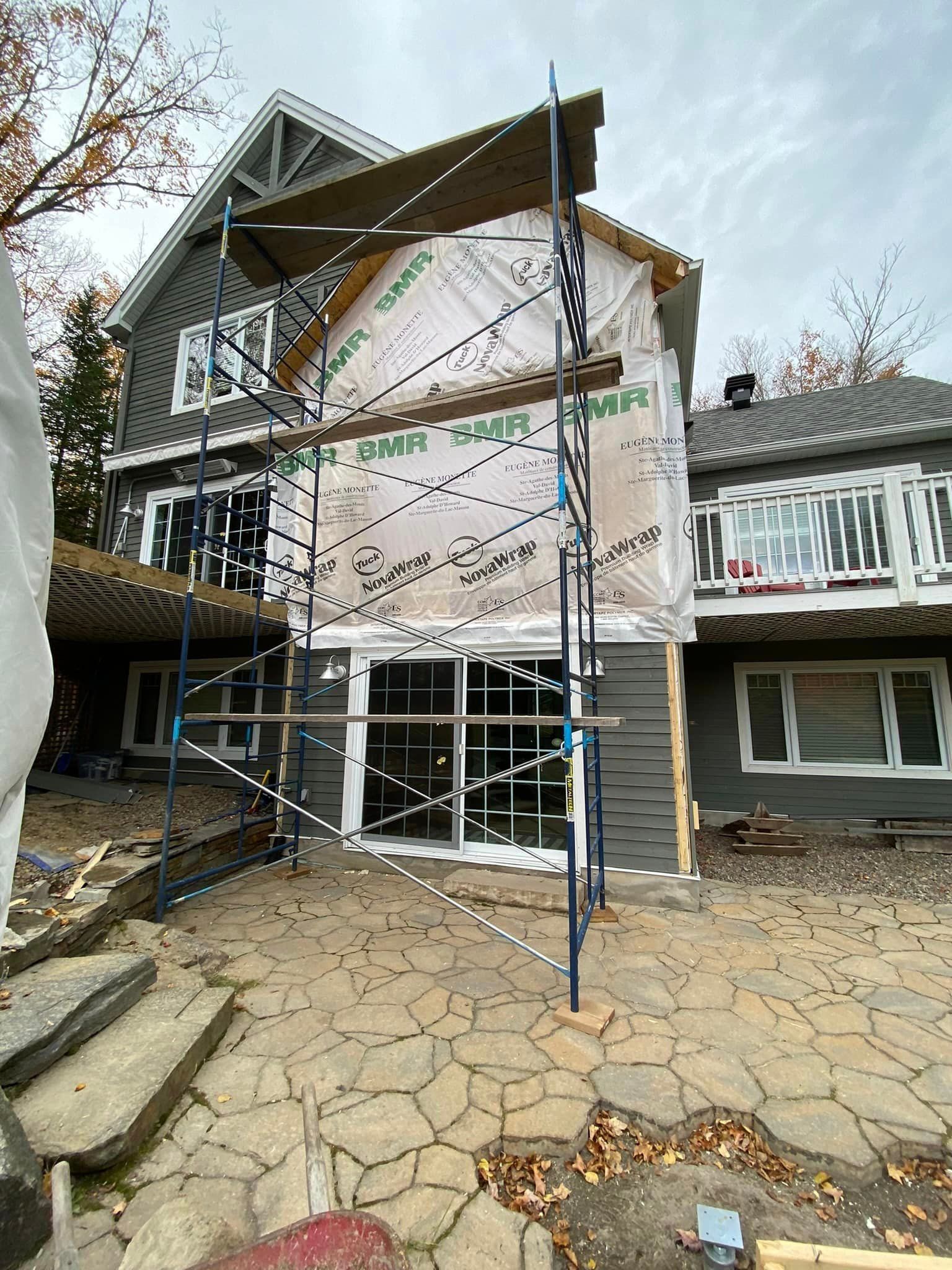 Une grande maison est en cours de rénovation avec des échafaudages autour.