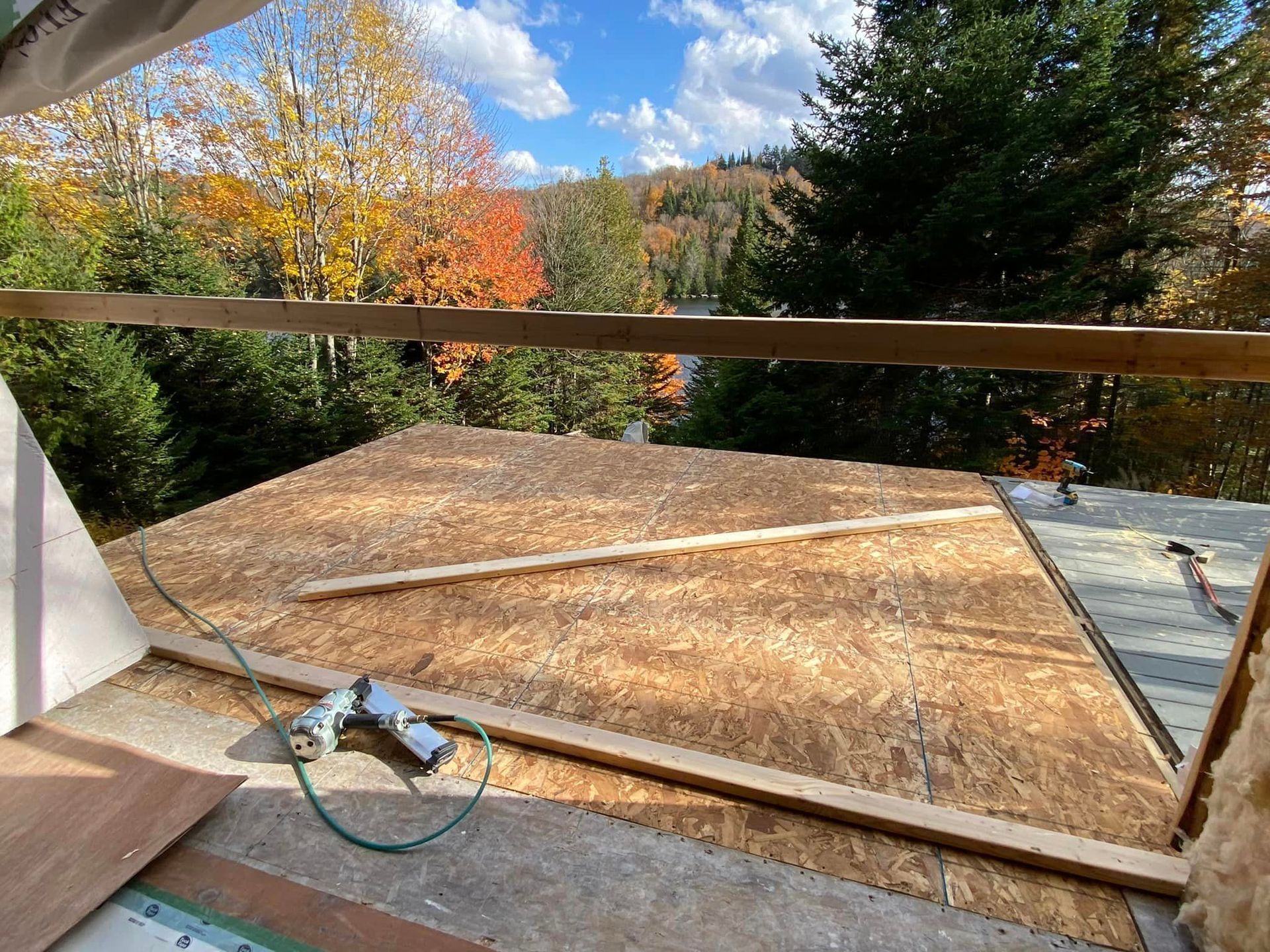 Un toit est en cours de construction avec vue sur un lac et des arbres en arrière-plan.