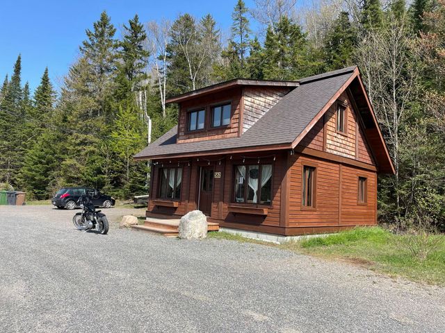 Une petite maison en bois avec une moto garée devant.