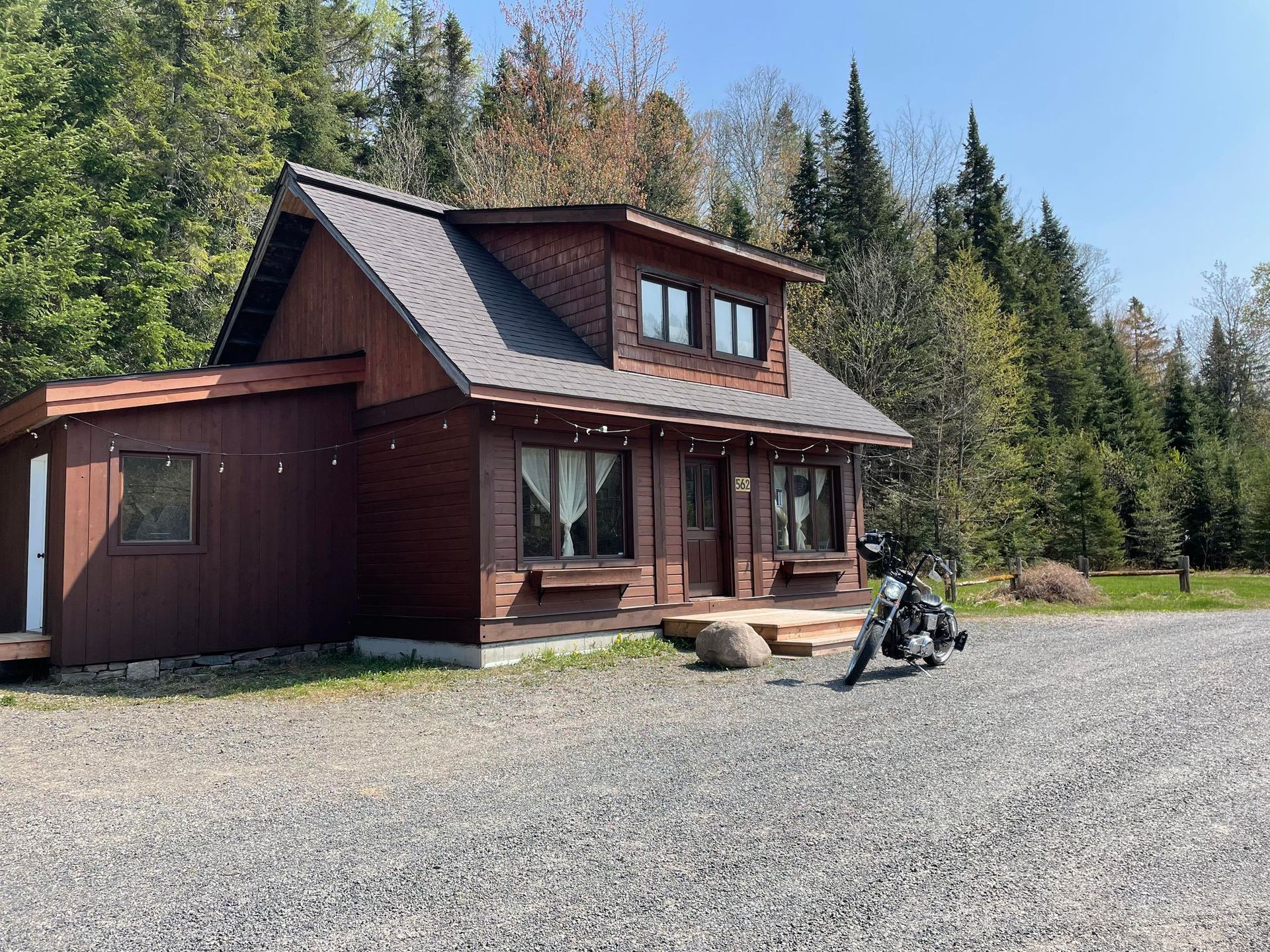 Une moto est garée devant une petite maison en bois.
