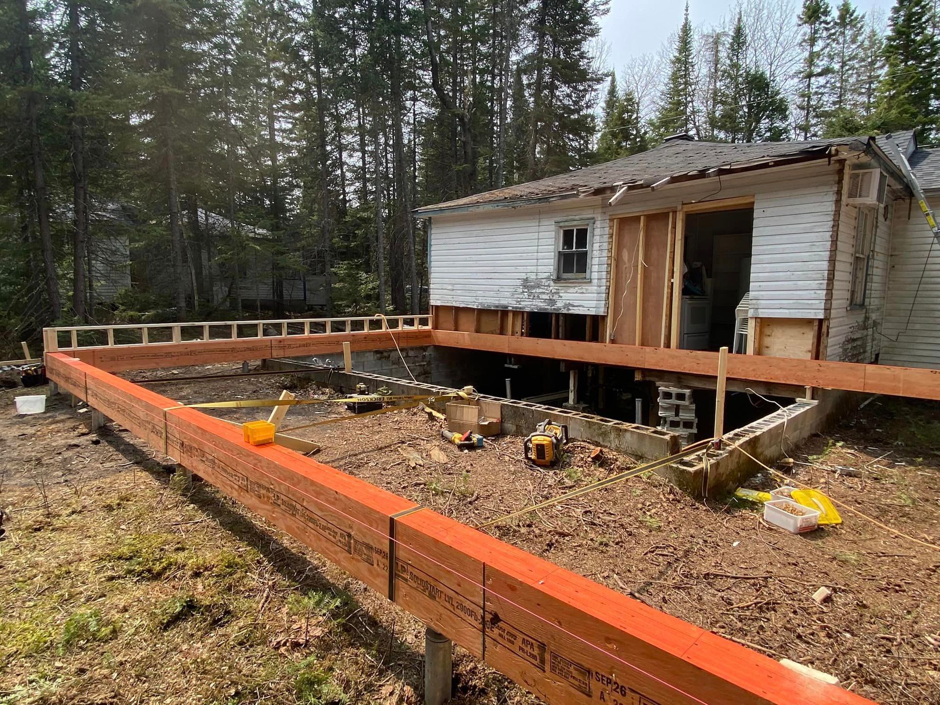 Une maison est en train d'être construite sur pilotis au milieu d'une forêt.