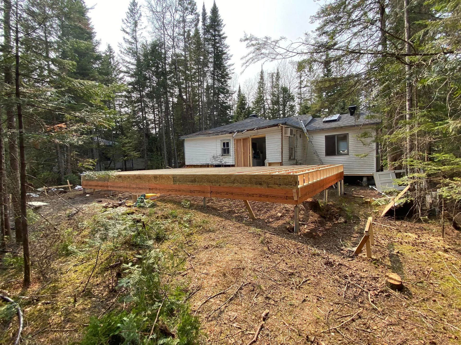 Une terrasse en bois est en cours de construction devant une maison dans les bois.