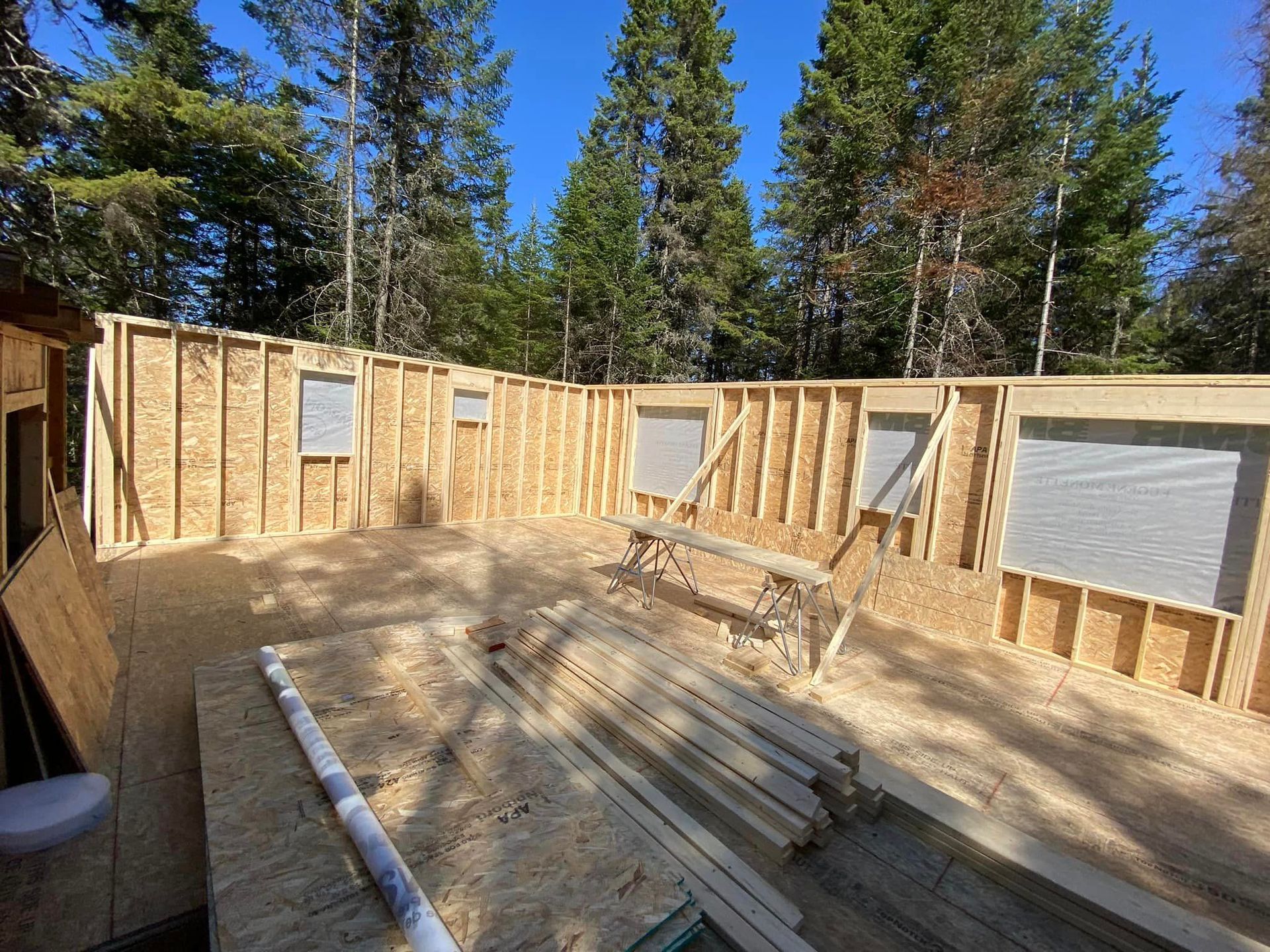 Une grande structure en bois est en train d'être construite au milieu d'une forêt.