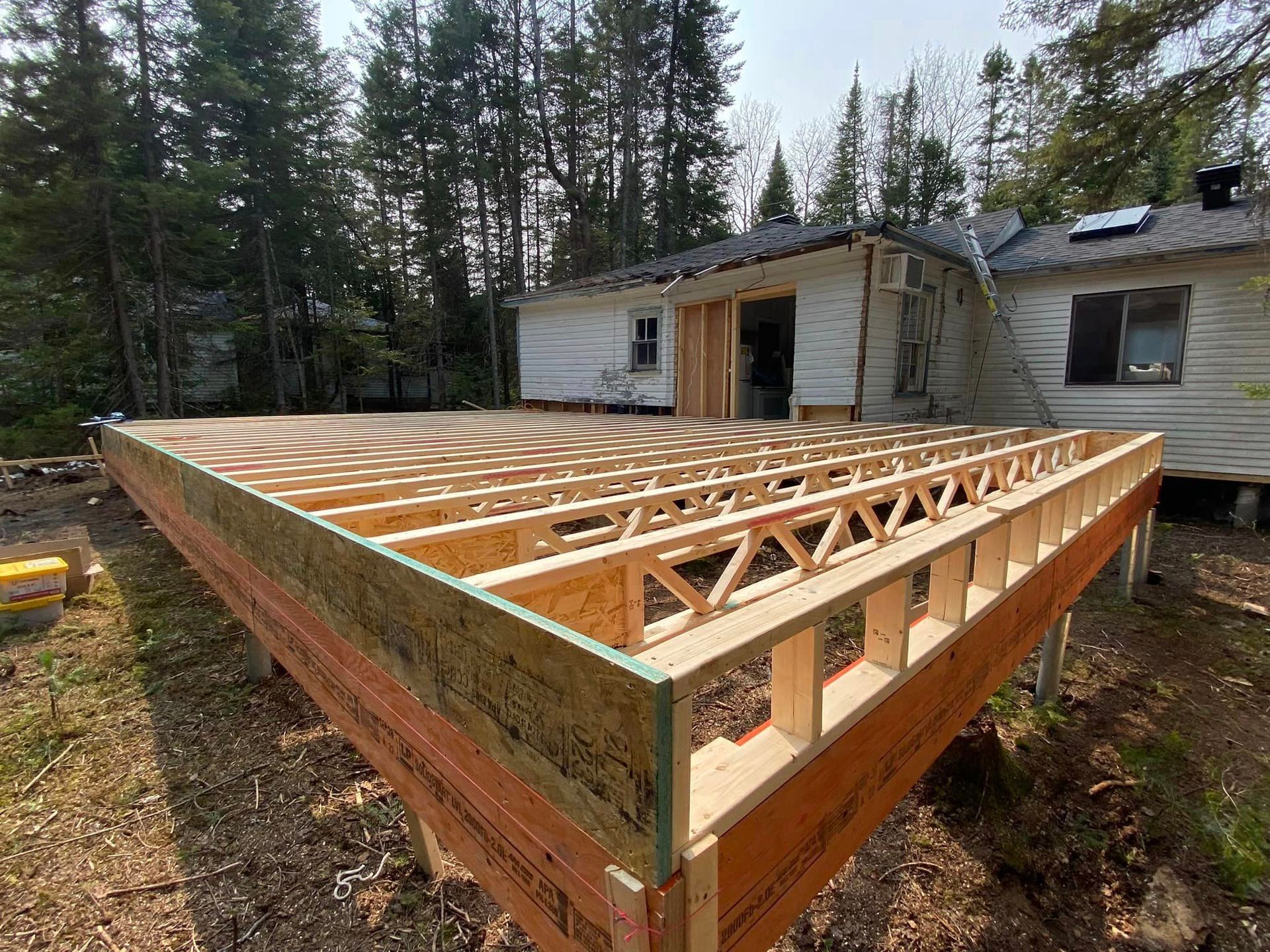 Une terrasse en bois est en cours de construction devant une maison.