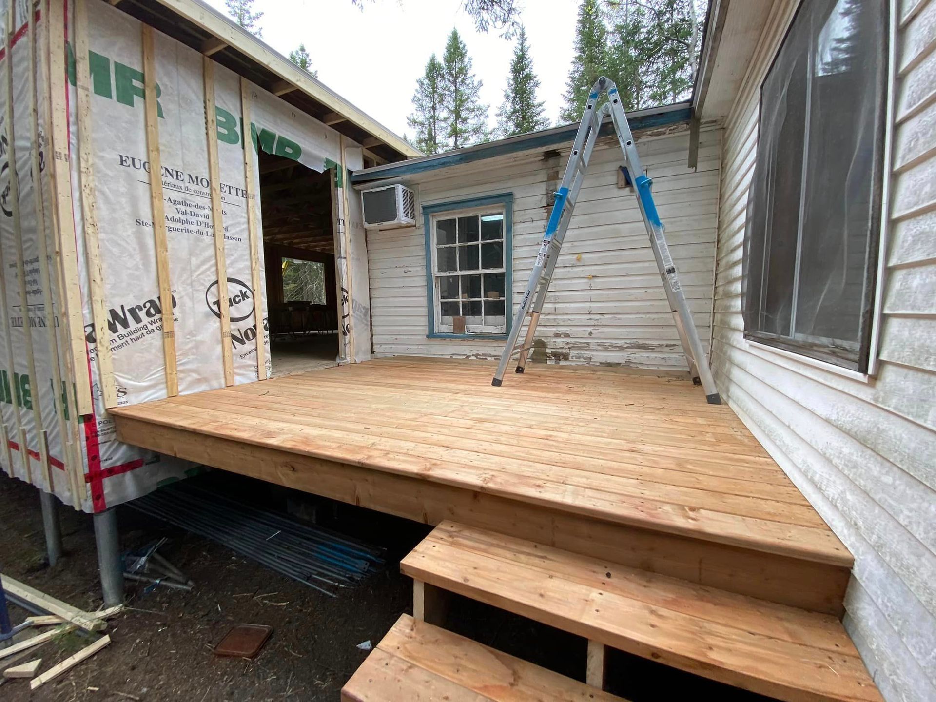 Une terrasse en bois est en cours de construction sur le côté d'une maison.