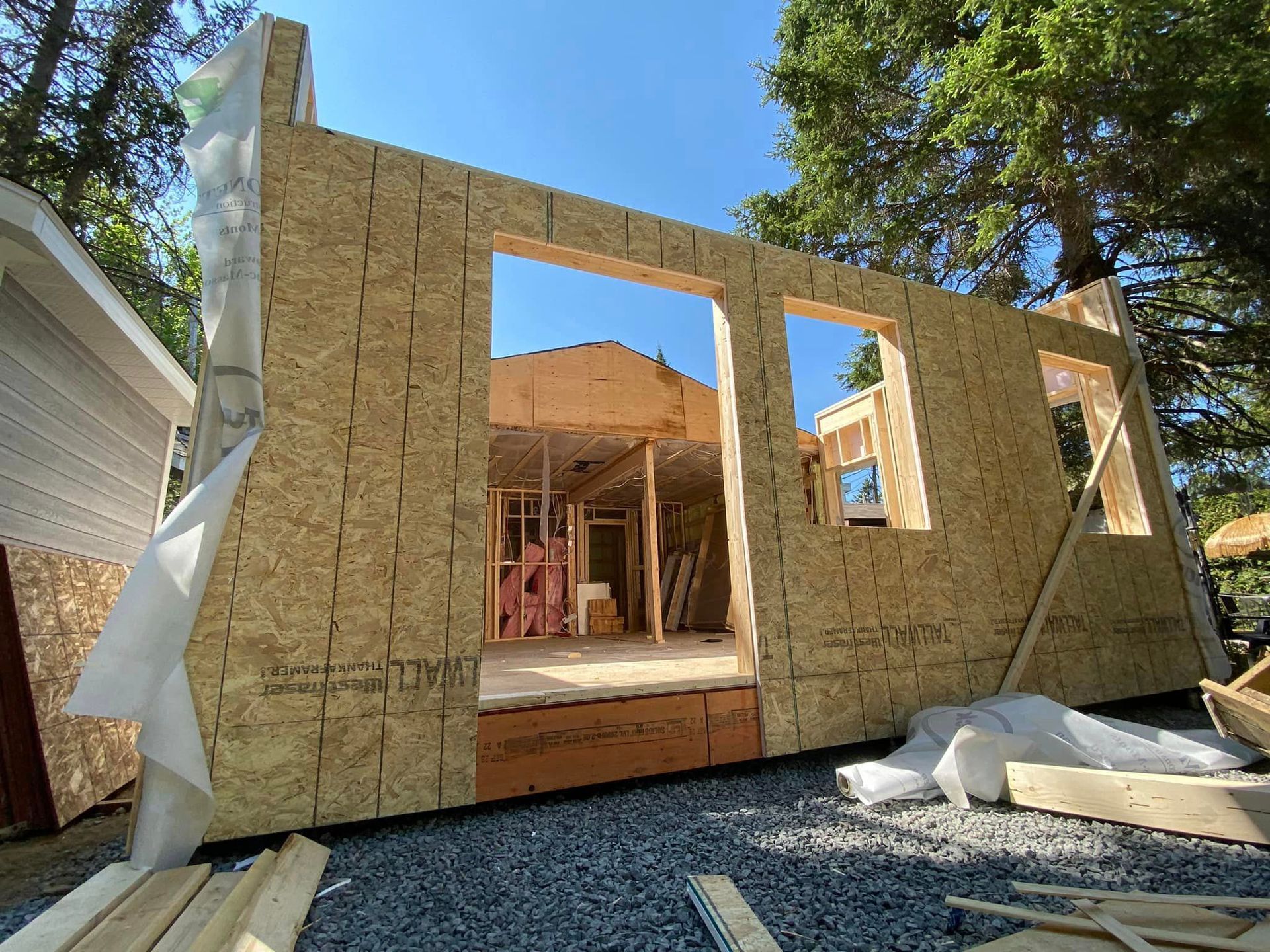 Une maison est en train d'être construite avec beaucoup de bois et beaucoup de fenêtres.