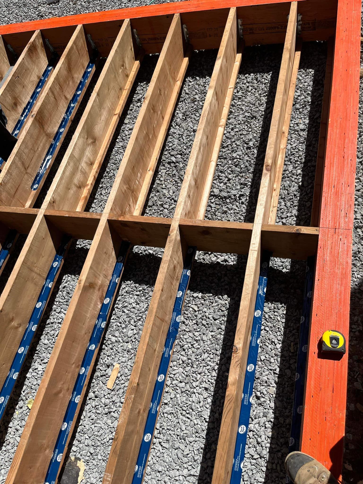 Une personne mesure une structure en bois avec un ruban à mesurer.