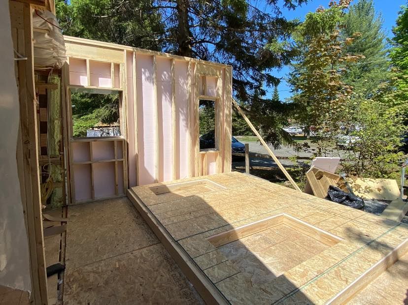 Une structure en bois est en cours de construction dans une cour arrière avec des arbres en arrière-plan.