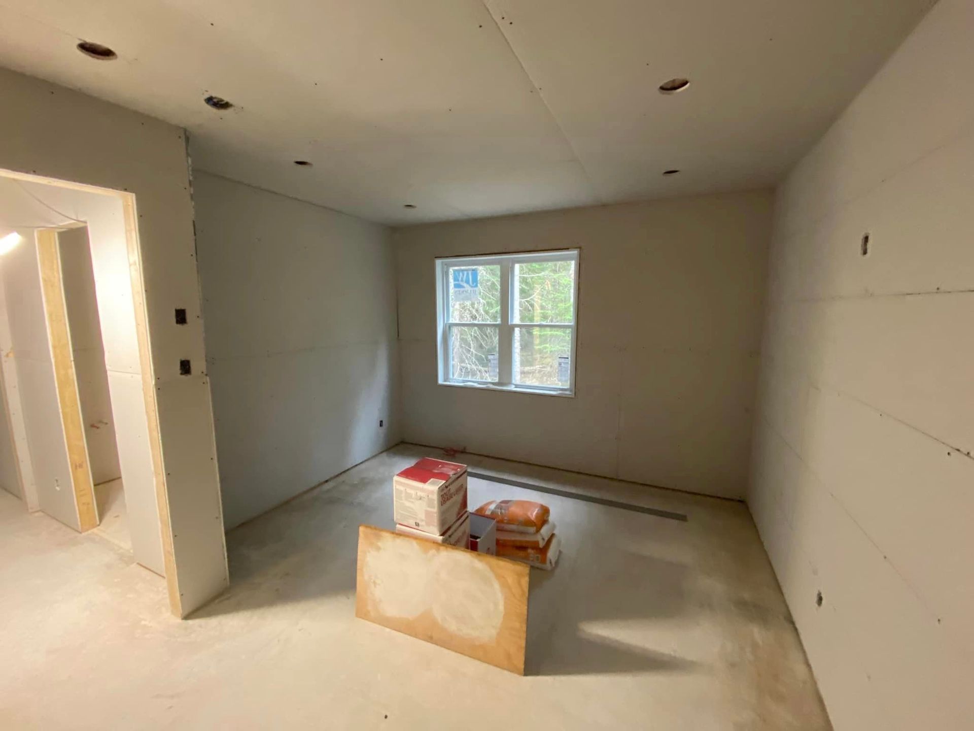 Une pièce en cours de rénovation avec des cloisons sèches et une fenêtre.