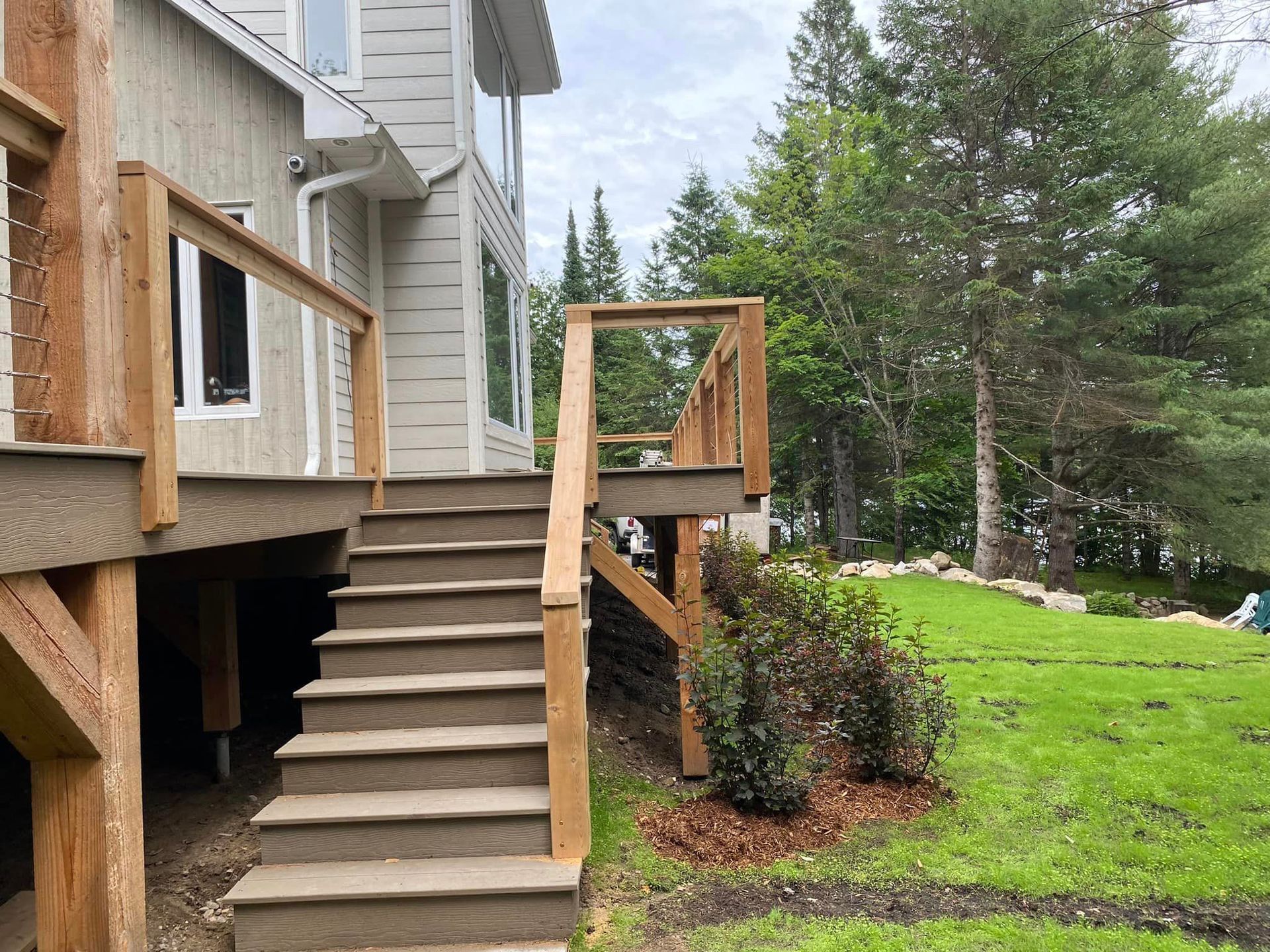 Une terrasse en bois avec des escaliers qui y mènent se trouve dans l'arrière-cour d'une maison.