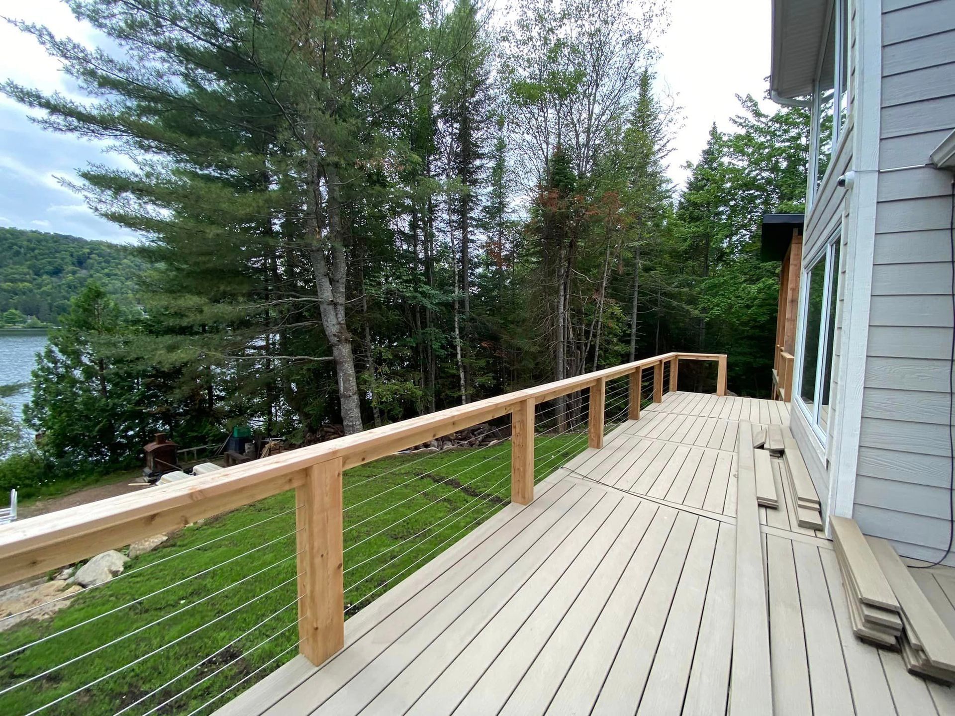 Une terrasse en bois avec une balustrade en métal donnant sur un lac