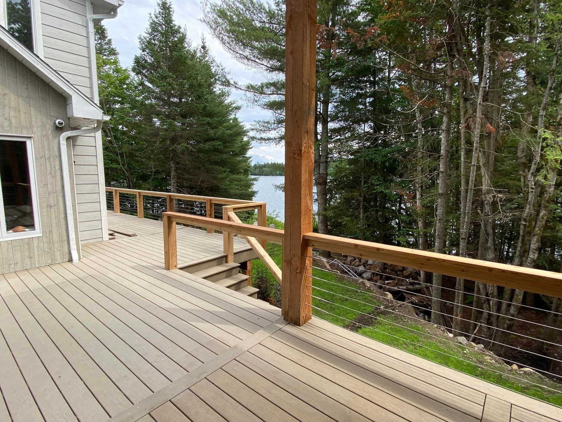 Une terrasse en bois avec vue sur un lac et des arbres.